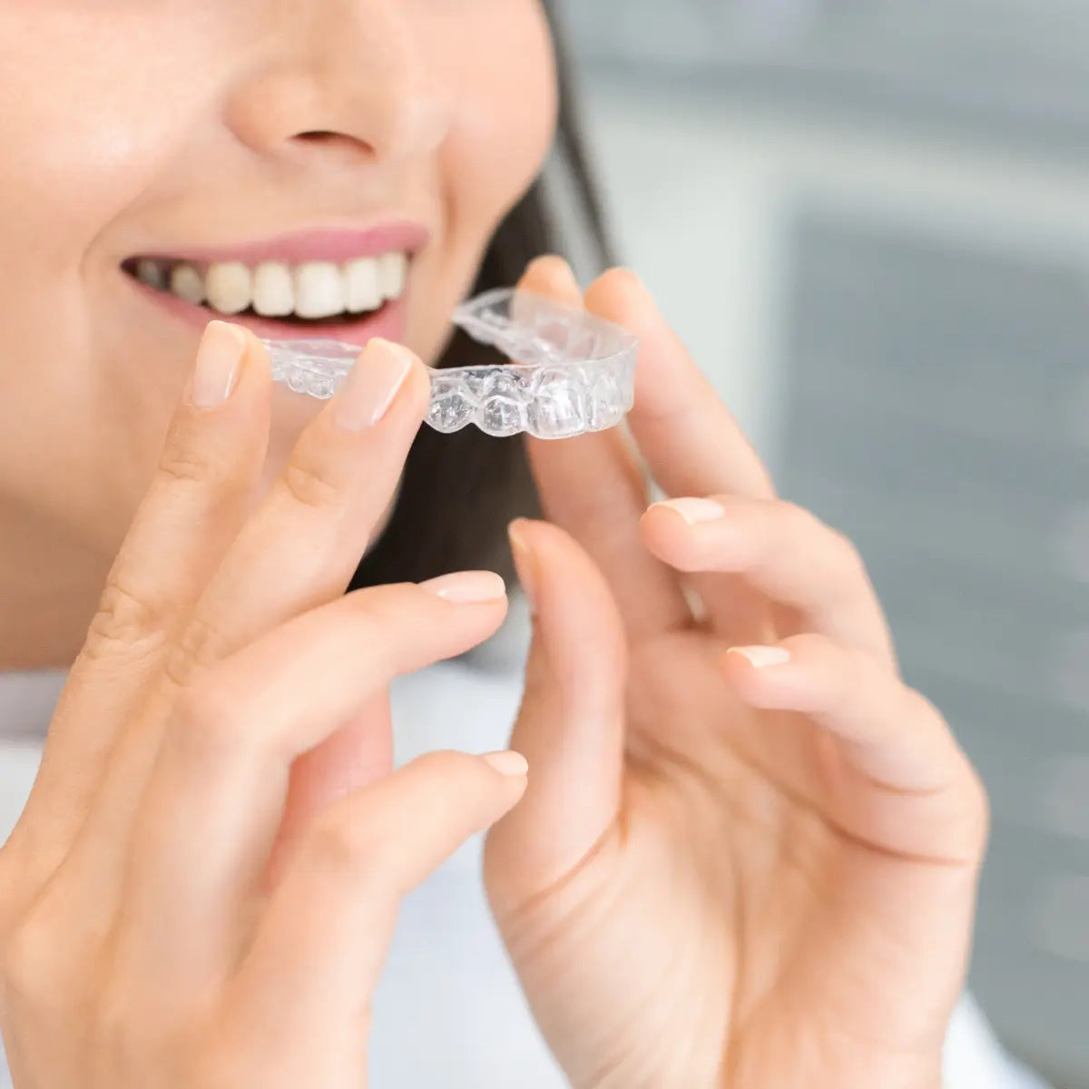 Woman with white teeth holding a dental cap